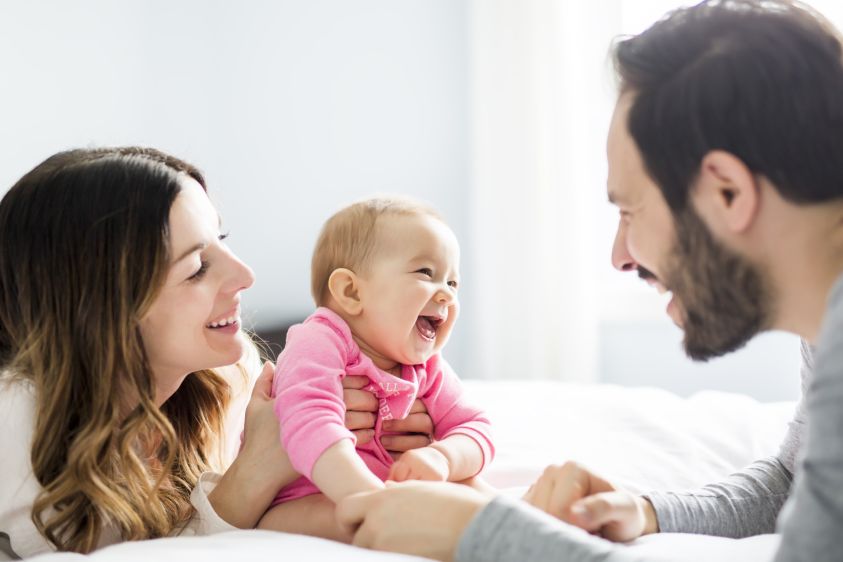 Mother father and baby child on a white bed2e00