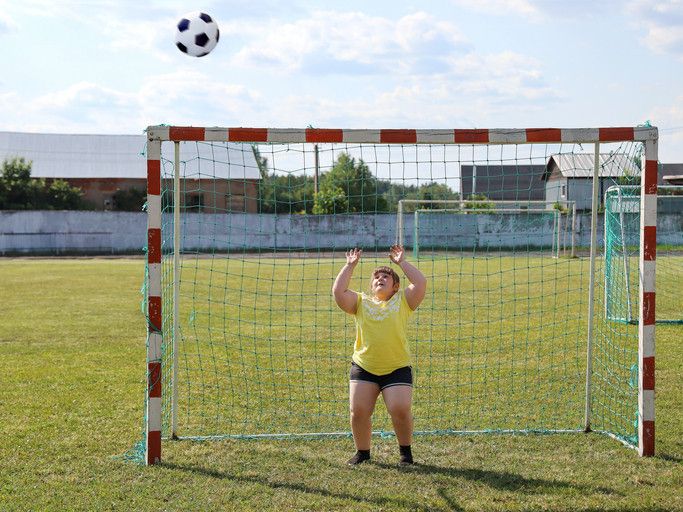 chlapec, sport,obezitat stands in football gate and wants to catch ball with his hands