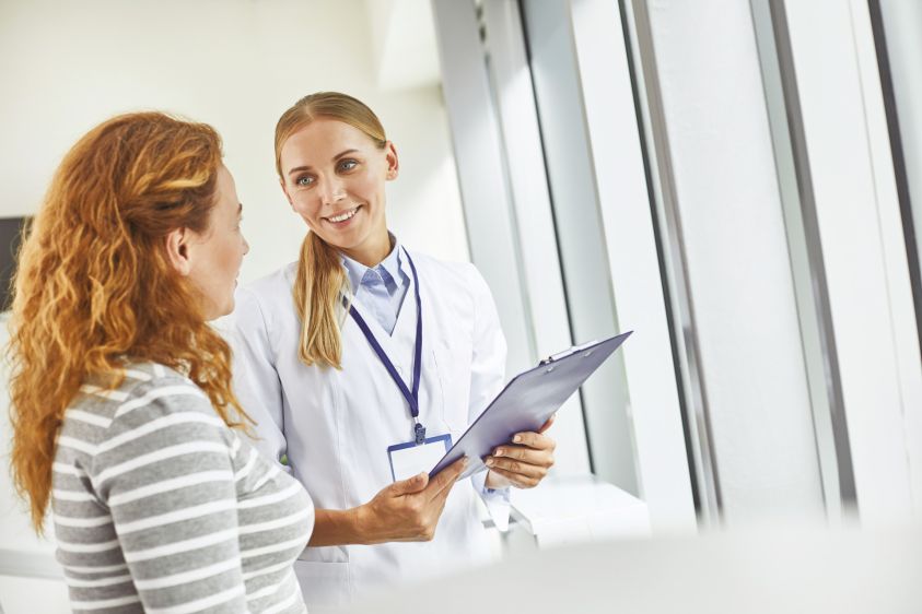 Young doctor holding clipboard while looking at patient